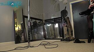 Brunette ballerina in black lingerie and hobble boots vacuums the house with long hair flowing.